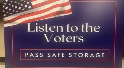 A sign says "Listen to the Voters. Pass safe storage."