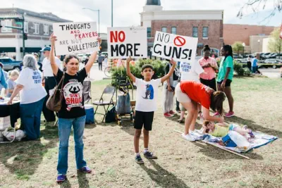 Kids protesting gun violence are holding signs that say "Thoughts and prayers are not bullet proof" and "No more. No guns!"