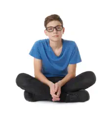 A teenage boy sits looking at the camera. The image represents young men and boys who commit suicide at a higher rate when firearms are available in their homes